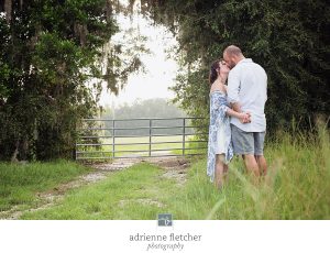 engaged couple kissing in a field