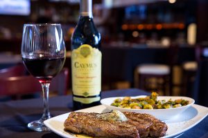 close up of steak dinner with wine bottle