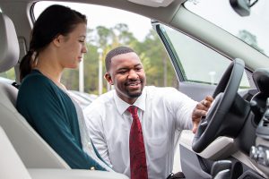 care salesman with customer showing car